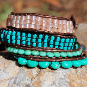 Megen Gabrielle Jewelry | Beaded woven wrap bracelet. Turquoise colored beads and silver medallion style button for closure. Also included in the photo; teal glass bead single layer wrap bracelet, glass blue beaded multi- layered wrap bracelet, and pink colored beaded multi- layered wrap bracelet