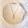 Gold necklaces with various pendants on a textured surface