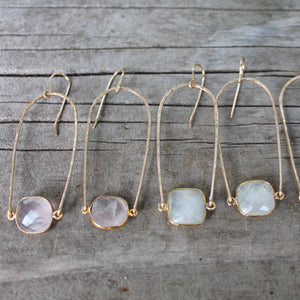 Megen Gabrielle Jewelry | Rainbow gemstone hoop earring. U- shaped (rainbow) earring hoop with gemstone mounted between. In the photo: 14K gold fill and 2 pairs of earrings, rose quartz, and moonstone.