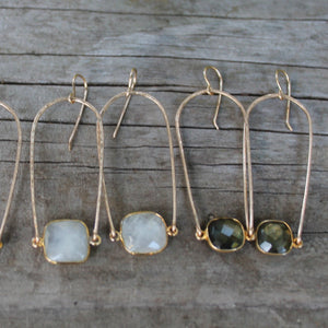 Megen Gabrielle Jewelry | Rainbow gemstone hoop earring. U- shaped (rainbow) earring hoop with gemstone mounted between. In the photo: 14K gold fill and 2 pairs of earrings, labradorite, and moonstone.